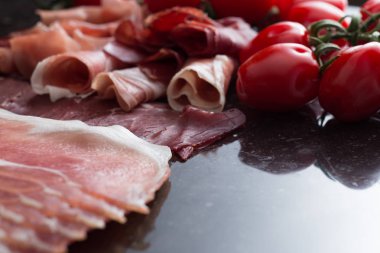 Jambon karışımı. Jambon. Geleneksel İtalyan ve İspanyol Tuzlama, Sigara, otlar ve karanlık taş zemin üzerine domates kuru tedavi çanak - jamon Serrano ve prosciutto crudo dilimlenmiş. Uzay kopyalayın. Portre