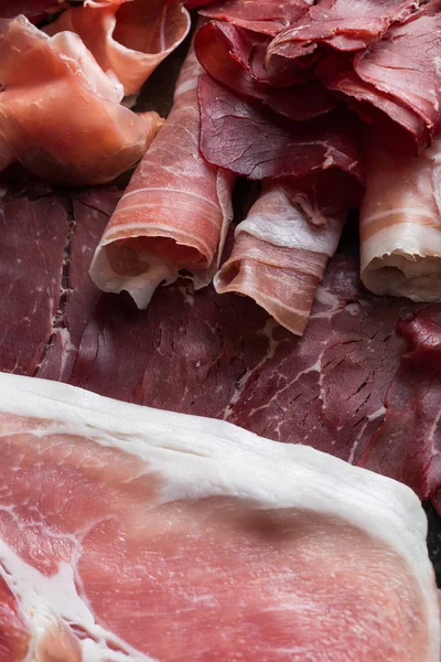 Jambon karışımı. Jambon. Geleneksel İtalyan ve İspanyol Tuzlama, Sigara, otlar ve karanlık taş zemin üzerine domates kuru tedavi çanak - jamon Serrano ve prosciutto crudo dilimlenmiş. Uzay kopyalayın. Portre