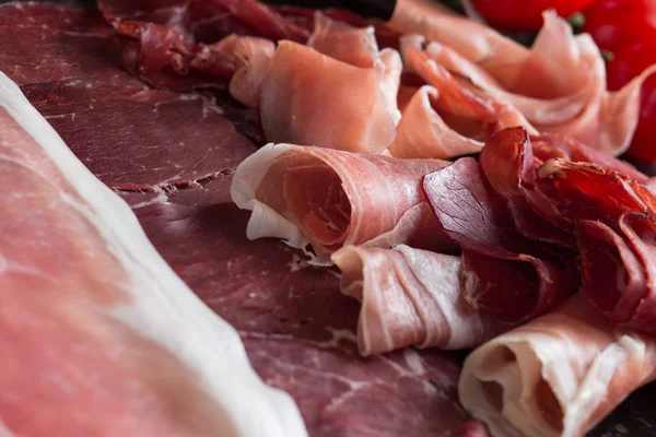 Jambon karışımı. Jambon. Geleneksel İtalyan ve İspanyol Tuzlama, Sigara, otlar ve karanlık taş zemin üzerine domates kuru tedavi çanak - jamon Serrano ve prosciutto crudo dilimlenmiş. Uzay kopyalayın. Portre