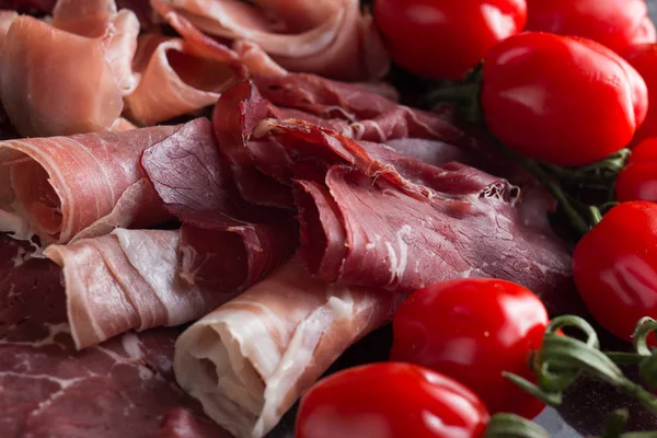 Jambon karışımı. Jambon. Geleneksel İtalyan ve İspanyol Tuzlama, Sigara, otlar ve karanlık taş zemin üzerine domates kuru tedavi çanak - jamon Serrano ve prosciutto crudo dilimlenmiş. Uzay kopyalayın. Portre