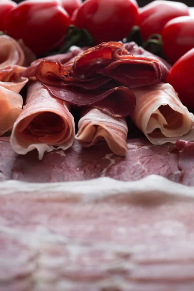 Jambon karışımı. Jambon. Geleneksel İtalyan ve İspanyol Tuzlama, Sigara, otlar ve karanlık taş zemin üzerine domates kuru tedavi çanak - jamon Serrano ve prosciutto crudo dilimlenmiş. Uzay kopyalayın. Portre