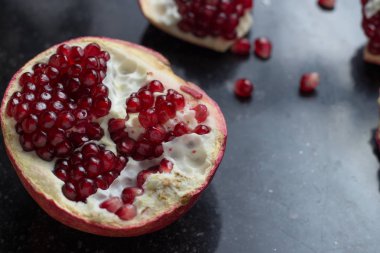 Karanlık mermer zemin üzerine kırmızı sulu nar. Sağlıklı, antioksidan, taze, gurme, lezzetli, organik meyve. Nar suyu için madde. Yakın çekim ve kopya alanı