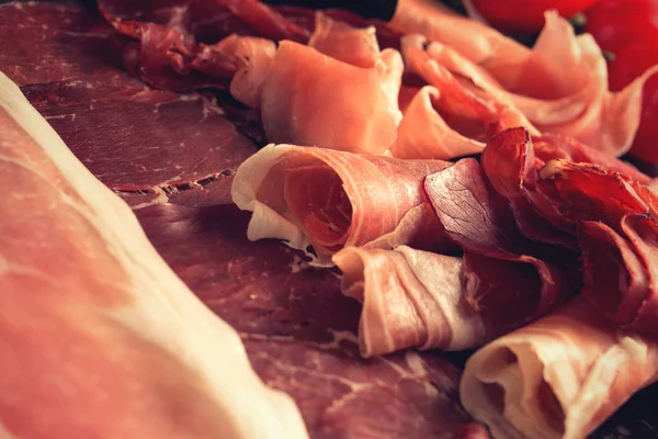 Jambon karışımı. Jambon. Geleneksel İtalyan ve İspanyol Tuzlama, Sigara, otlar ve karanlık taş zemin üzerine domates kuru tedavi çanak - jamon Serrano ve prosciutto crudo dilimlenmiş. Uzay kopyalayın. Portre