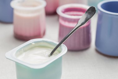 Plastik yoğurt ürün yelpazesine beyaz Tekstil arka plan üzerinde kaseler. Doğal ve sağlıklı meyve, diyet, gurme tatlı granola kahvaltı için. Tatlı yoğurt portre