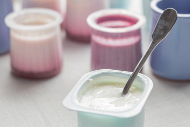 Plastik yoğurt ürün yelpazesine beyaz Tekstil arka plan üzerinde kaseler. Doğal ve sağlıklı meyve, diyet, gurme tatlı granola kahvaltı için. Tatlı yoğurt portre