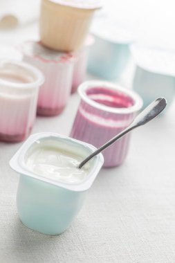 Doğal ve meyve yoğurt çeşitler plastik kase beyaz Tekstil arka plan üzerinde. Sağlıklı, diyet, gurme tatlı granola kahvaltı için. Tatlı yoğurt portre