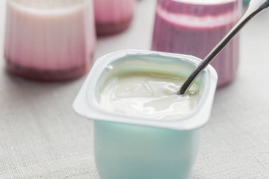 Plastik yoğurt ürün yelpazesine beyaz Tekstil arka plan üzerinde kaseler. Doğal ve sağlıklı meyve, diyet, gurme tatlı granola kahvaltı için. Tatlı yoğurt portre