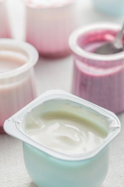 Plastik yoğurt ürün yelpazesine beyaz Tekstil arka plan üzerinde kaseler. Doğal ve sağlıklı meyve, diyet, gurme tatlı granola kahvaltı için. Tatlı yoğurt portre