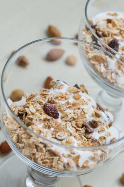 Granola yoğurt, fındık ve açık renkli cam kase meyve ile. Kahvaltı için lezzetli, sağlıklı tatlı tatlı. Mısır gevreği, müsli. Kopya alanı, portre