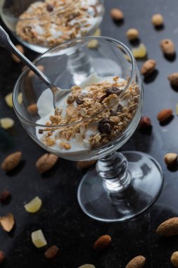 Granola yoğurt, fındık ve koyu arka plan üzerinde cam kase meyve ile. Kahvaltı için lezzetli, sağlıklı tatlı tatlı. Mısır gevreği, müsli. Kopya alanı, portre