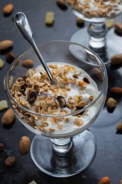 Granola yoğurt, fındık ve koyu arka plan üzerinde cam kase meyve ile. Kahvaltı için lezzetli, sağlıklı tatlı tatlı. Mısır gevreği, müsli. Kopya alanı, portre