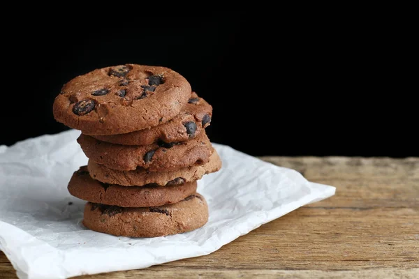 Cookies avec pépites de chocolat sur serviette en papier parchemin sur table en bois — Photo