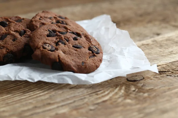 Cookies avec pépites de chocolat sur serviette en papier parchemin sur table en bois — Photo