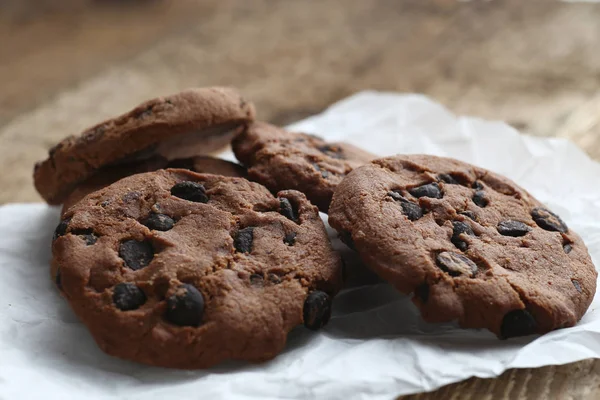 Cookies avec pépites de chocolat sur serviette en papier parchemin sur table en bois — Photo