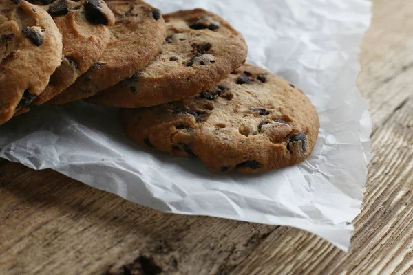 Cookies avec pépites de chocolat sur serviette en papier parchemin sur table en bois — Photo