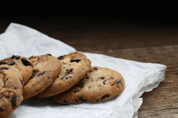 Cookies avec pépites de chocolat sur serviette en papier parchemin sur table en bois — Photo