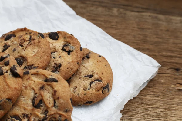 Cookies avec pépites de chocolat sur serviette en papier parchemin sur table en bois — Photo