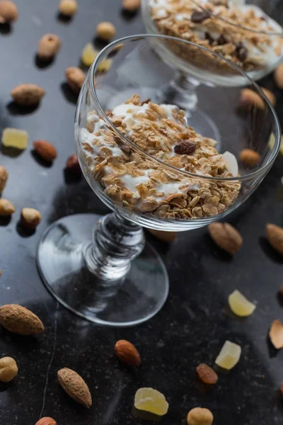 Granola yoğurt, fındık ve koyu arka plan üzerinde cam kase meyve ile. Kahvaltı için lezzetli, sağlıklı tatlı tatlı. Mısır gevreği, müsli. Kopya alanı, portre