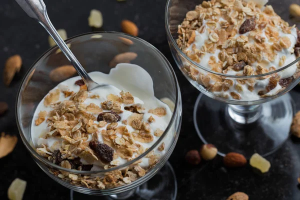 Granola yoğurt, fındık ve koyu arka plan üzerinde cam kase meyve ile. Kahvaltı için lezzetli, sağlıklı tatlı tatlı. Mısır gevreği, müsli. Kopya alanı, portre