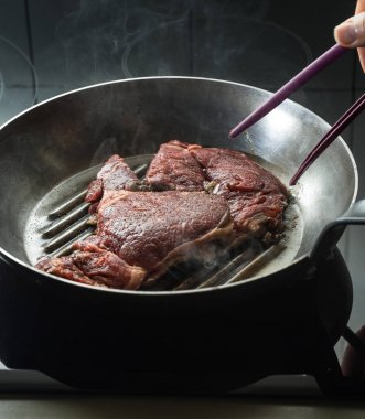 Izgara biftek ızgara tava üzerinde. Bir mutfak pişirme biftek. Kopyalama alanı closeup ile taze, lezzetli, baharatlı, sulu et