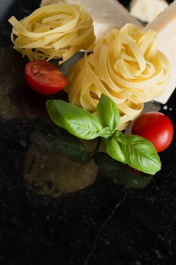 Makarna Tagliatelle, parmesan mermer masaya düzenlenmiştir. Geleneksel İtalyan mutfağı yemek için lezzetli kuru pişmemiş maddeler. Ham closeup arka plan. Üstten Görünüm. Kopya alanı