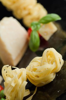 Makarna Tagliatelle, parmesan mermer masaya düzenlenmiştir. Geleneksel İtalyan mutfağı yemek için lezzetli kuru pişmemiş maddeler. Ham closeup arka plan. Üstten Görünüm. Kopya alanı