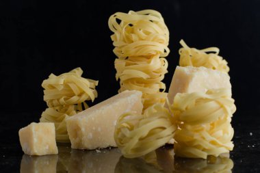Makarna Tagliatelle, parmesan mermer masaya düzenlenmiştir. Geleneksel İtalyan mutfağı yemek için lezzetli kuru pişmemiş maddeler. Ham closeup arka plan. Üstten Görünüm. Kopya alanı