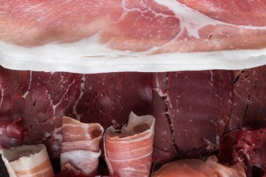 Jambon karışımı. Jambon. Geleneksel İtalyan ve İspanyol Tuzlama, Sigara, otlar ve karanlık taş zemin üzerine domates kuru tedavi çanak - jamon Serrano ve prosciutto crudo dilimlenmiş. Uzay kopyalayın. Portre