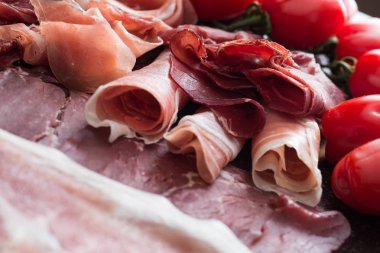 Jambon karışımı. Jambon. Geleneksel İtalyan ve İspanyol Tuzlama, Sigara, otlar ve karanlık taş zemin üzerine domates kuru tedavi çanak - jamon Serrano ve prosciutto crudo dilimlenmiş. Uzay kopyalayın. Portre