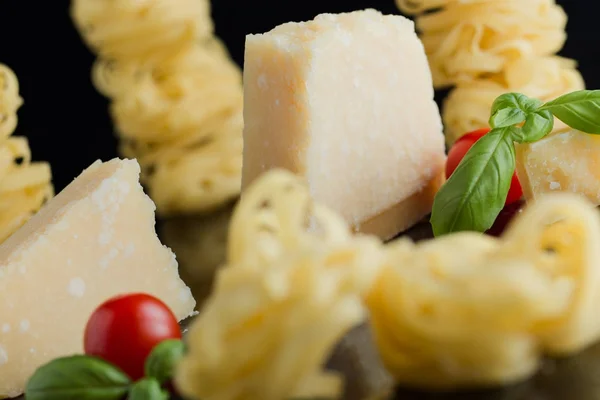 Pasta Tagliatelle, parmesan arranged on marble table. Delicious dry uncooked ingredients for traditional Italian cuisine dish. Raw closeup background. Top view. Copy space — Stock Photo, Image