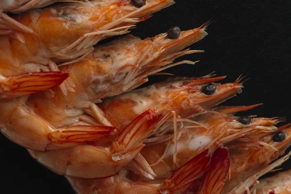 Shrimps on black background. Delicious seafood appetizer served boiled or grilled with spices. Close up. Top view — Stock Photo, Image