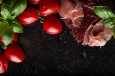 Jambon karışımı. Jambon. Geleneksel İtalyan ve İspanyol Tuzlama, Sigara, otlar ve karanlık taş zemin üzerine domates kuru tedavi çanak - jamon Serrano ve prosciutto crudo dilimlenmiş. Uzay kopyalayın. Portre