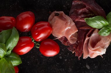 Jambon karışımı. Jambon. Geleneksel İtalyan ve İspanyol Tuzlama, Sigara, otlar ve karanlık taş zemin üzerine domates kuru tedavi çanak - jamon Serrano ve prosciutto crudo dilimlenmiş. Uzay kopyalayın. Portre
