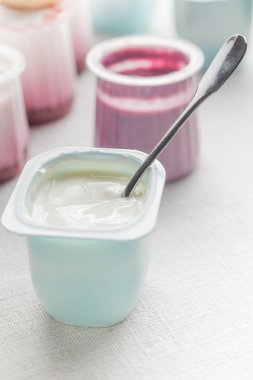 Plastik yoğurt ürün yelpazesine beyaz Tekstil arka plan üzerinde kaseler. Doğal ve sağlıklı meyve, diyet, gurme tatlı granola kahvaltı için. Tatlı yoğurt portre