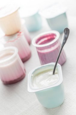Plastik yoğurt ürün yelpazesine beyaz Tekstil arka plan üzerinde kaseler. Doğal ve sağlıklı meyve, diyet, gurme tatlı granola kahvaltı için. Tatlı yoğurt portre