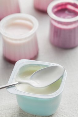 Plastik yoğurt ürün yelpazesine beyaz Tekstil arka plan üzerinde kaseler. Doğal ve sağlıklı meyve, diyet, gurme tatlı granola kahvaltı için. Tatlı yoğurt portre