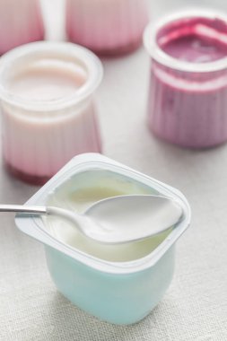 Plastik yoğurt ürün yelpazesine beyaz Tekstil arka plan üzerinde kaseler. Doğal ve sağlıklı meyve, diyet, gurme tatlı granola kahvaltı için. Tatlı yoğurt portre