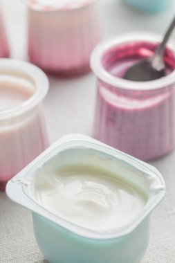 Plastik yoğurt ürün yelpazesine beyaz Tekstil arka plan üzerinde kaseler. Doğal ve sağlıklı meyve, diyet, gurme tatlı granola kahvaltı için. Tatlı yoğurt portre