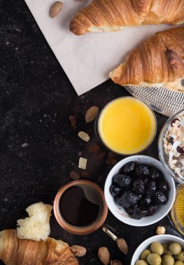 Kahvaltı çeşitli yoğurt, granola, kahve, meyve suyu, kruvasan, zeytin. Meze sabah yemekleri ile karıştırın. Koyu arka plan üzerinde sağlıklı, taze, lezzetli yemek. Üstten Görünüm. Kopya alanı