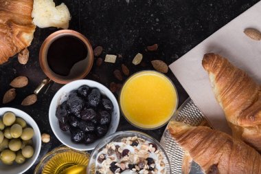 Kahvaltı çeşitli yoğurt, granola, kahve, meyve suyu, kruvasan, zeytin. Meze sabah yemekleri ile karıştırın. Koyu arka plan üzerinde sağlıklı, taze, lezzetli yemek. Üstten Görünüm. Kopya alanı