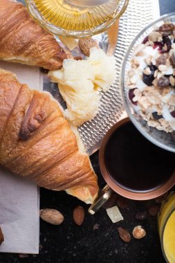 Kahvaltı çeşitli yoğurt, granola, kahve, meyve suyu, kruvasan, zeytin. Meze sabah yemekleri ile karıştırın. Koyu arka plan üzerinde sağlıklı, taze, lezzetli yemek. Üstten Görünüm. Kopya alanı