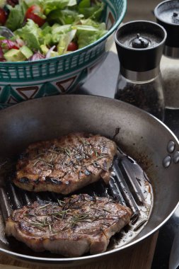 Biftek salata ve baharat ile karanlık tabloda. Taze, lezzetli pişmiş et kopya alanı closeup ile bir ızgara üzerinde