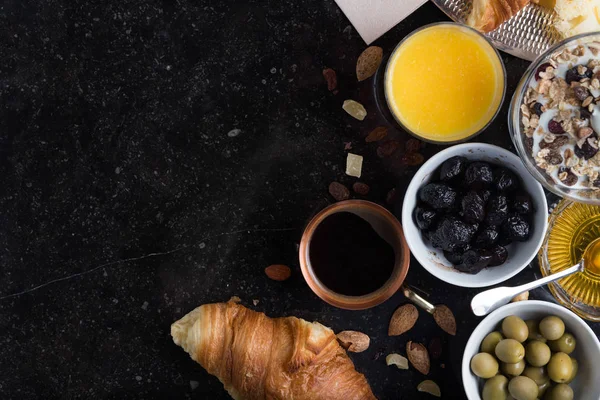 Colazione assortiti yogurt, muesli, caffè, succo di frutta, croissant, olive. Miscela antipasto con piatti del mattino. Cibo sano, fresco e delizioso su sfondo scuro. Vista dall'alto. Copia spazio — Foto Stock