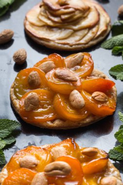 Kayısı ve elma tart. Karanlık mermer zemin üzerine meyve ile geleneksel Fransız pasta. Bir şekilde dekore edilmiş badem ve nane yaprakları. Kopyalama alanı closeup ile lezzetli tatlı