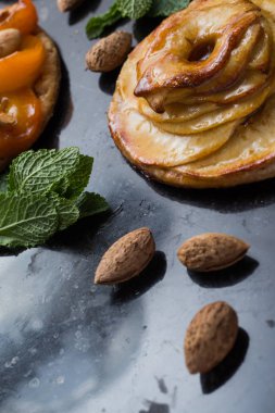 Kayısı ve elma tart. Karanlık mermer zemin üzerine meyve ile geleneksel Fransız pasta. Bir şekilde dekore edilmiş badem ve nane yaprakları. Kopyalama alanı closeup ile lezzetli tatlı