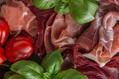 Jambon karışımı. Jambon. Geleneksel İtalyan ve İspanyol Tuzlama, Sigara, otlar ve karanlık taş zemin üzerine domates kuru tedavi çanak - jamon Serrano ve prosciutto crudo dilimlenmiş. Uzay kopyalayın. Portre