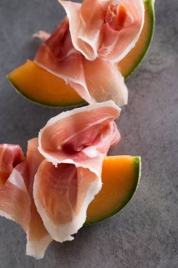 Jambon karışımı. Jambon. Geleneksel İtalyan ve İspanyol Tuzlama, Sigara, Kuru tedavi çanak - jamon Serrano ve prosciutto crudo gri arka plan üzerinde kavun ile dilimlenmiş. Uzay kopyalayın. Portre