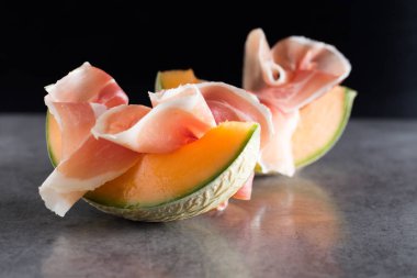 Jambon mix. Ham. Traditional Italian and Spanish salting, smoking, dry-cured dish - jamon Serrano and prosciutto crudo sliced with melon on grey background. Copy space. Closeup clipart