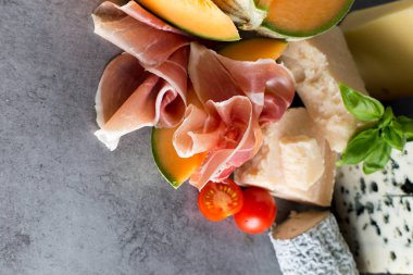 Jambon karışımı. Jambon. Geleneksel İtalyan ve İspanyol Tuzlama, Sigara, Kuru tedavi çanak - jamon Serrano ve prosciutto crudo gri arka plan üzerinde kavun ile dilimlenmiş. Uzay kopyalayın. Portre