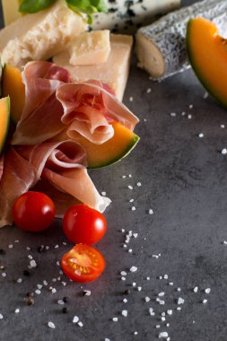 Jambon karışımı. Jambon. Geleneksel İtalyan ve İspanyol Tuzlama, Sigara, Kuru tedavi çanak - jamon Serrano ve prosciutto crudo gri arka plan üzerinde kavun ile dilimlenmiş. Uzay kopyalayın. Portre